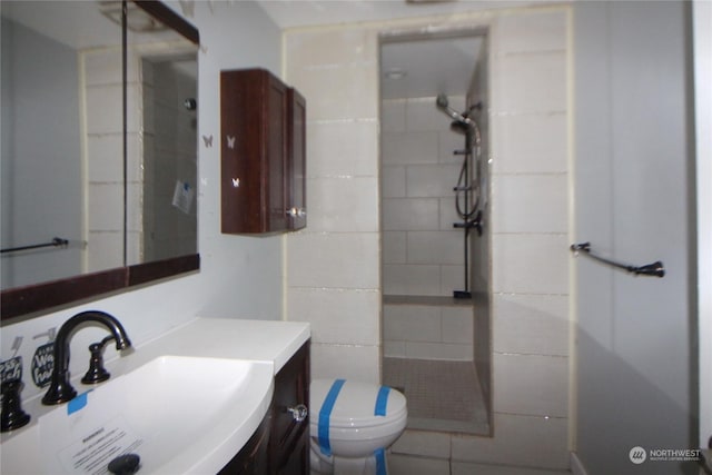 bathroom with vanity, tiled shower, and toilet