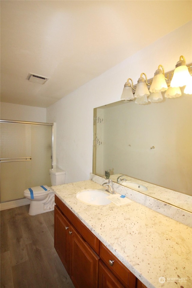 bathroom with vanity, toilet, hardwood / wood-style floors, and a shower with shower door