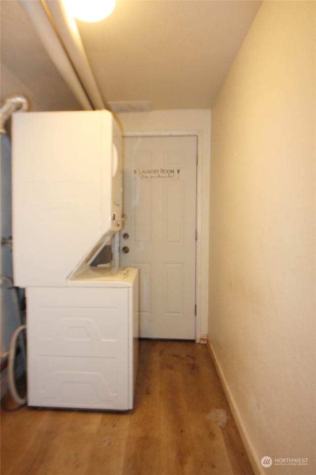 clothes washing area with stacked washer and clothes dryer and hardwood / wood-style floors