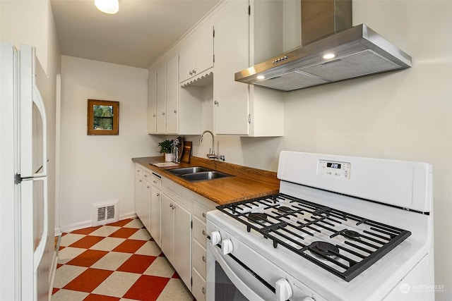 kitchen with white cabinetry, white appliances, sink, and wall chimney range hood