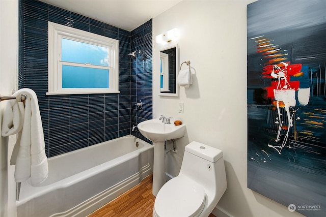 bathroom featuring toilet, tiled shower / bath combo, and hardwood / wood-style floors