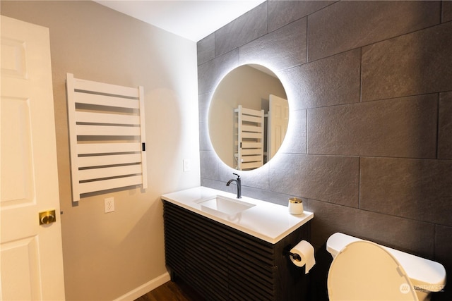 bathroom with radiator heating unit, toilet, vanity, and tile walls