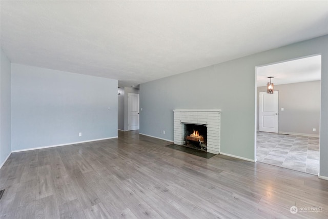 unfurnished living room featuring a brick fireplace and light wood-type flooring