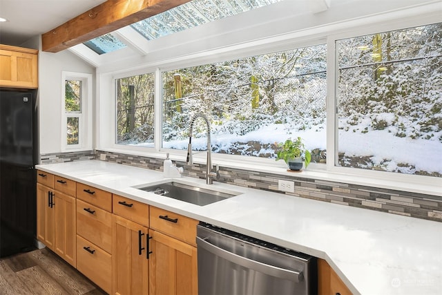 kitchen featuring backsplash, lofted ceiling with skylight, freestanding refrigerator, a sink, and dishwasher