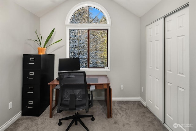 carpeted office space featuring vaulted ceiling and baseboards