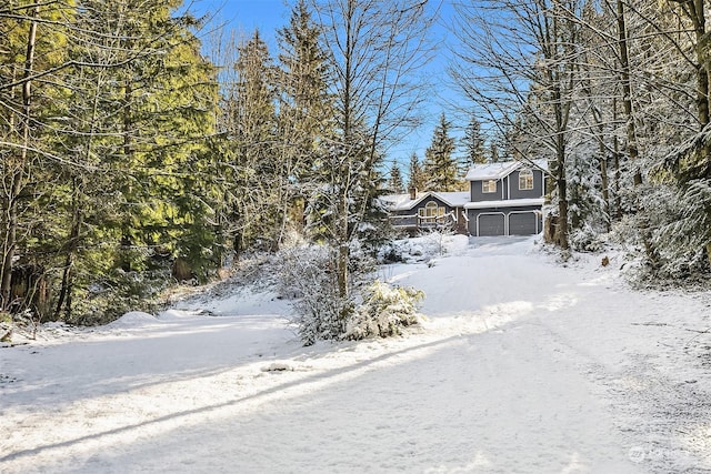 yard layered in snow featuring an attached garage