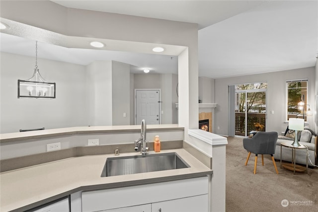 kitchen featuring pendant lighting, sink, light carpet, and white cabinets