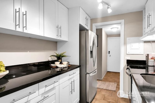 kitchen with white cabinetry, dark stone counters, stove, light tile patterned floors, and stainless steel fridge with ice dispenser