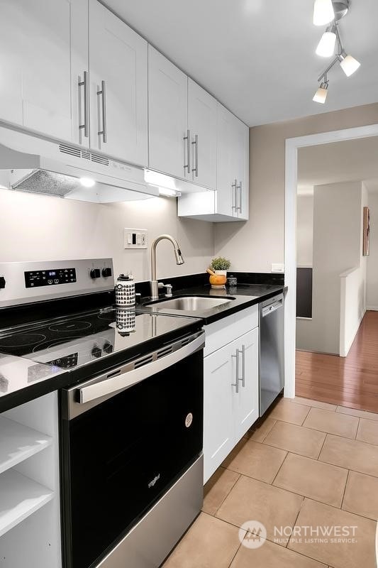 kitchen with light tile patterned flooring, appliances with stainless steel finishes, sink, and white cabinets