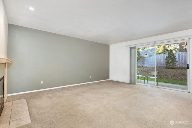 unfurnished living room with carpet flooring and a tiled fireplace