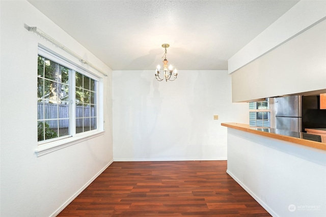 unfurnished dining area featuring an inviting chandelier and dark hardwood / wood-style floors