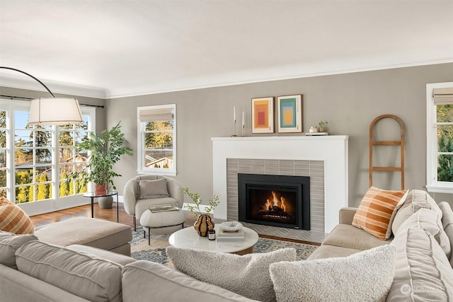 living room featuring crown molding, a tiled fireplace, and hardwood / wood-style flooring