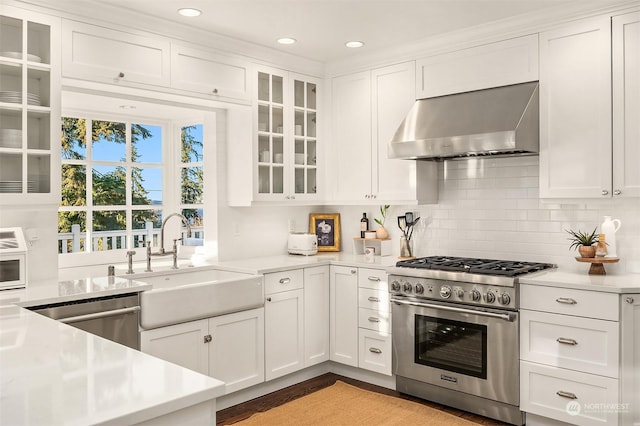 kitchen with sink, stainless steel appliances, white cabinets, and wall chimney exhaust hood