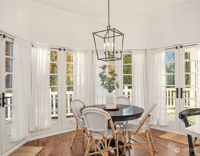 dining space with a healthy amount of sunlight, an inviting chandelier, dark hardwood / wood-style flooring, and french doors