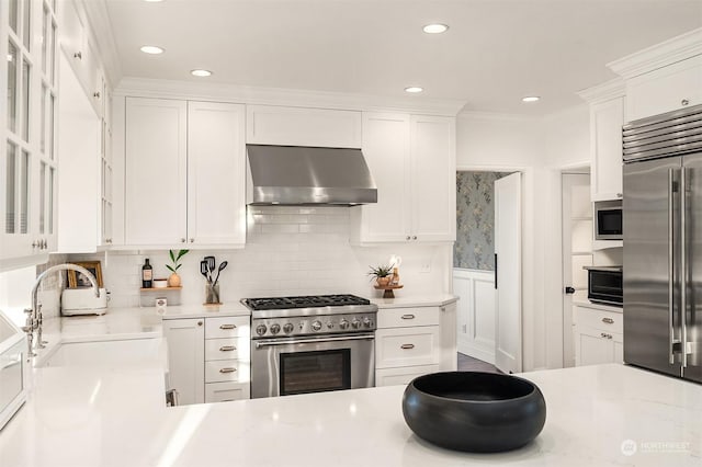 kitchen featuring sink, white cabinetry, built in appliances, decorative backsplash, and exhaust hood