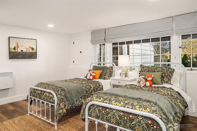 bedroom featuring heating unit and wood-type flooring