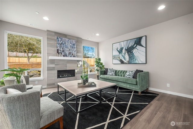 living area with visible vents, baseboards, a tiled fireplace, recessed lighting, and wood finished floors