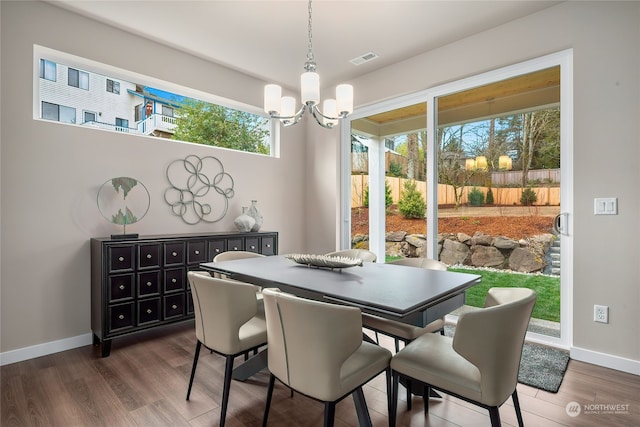 dining room featuring a notable chandelier, wood finished floors, visible vents, and baseboards