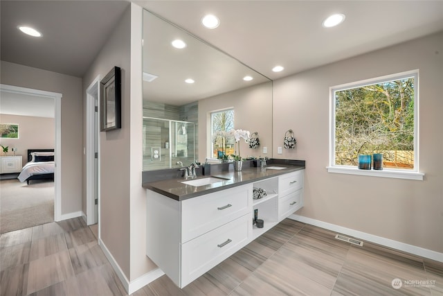 bathroom with a shower stall, double vanity, visible vents, and a sink