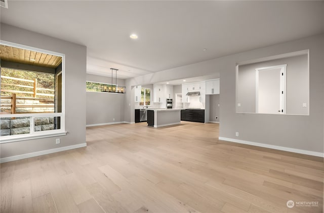 unfurnished living room with recessed lighting, light wood-style floors, baseboards, and a notable chandelier