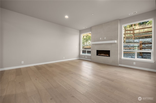 unfurnished living room featuring visible vents, baseboards, light wood-style flooring, and a fireplace