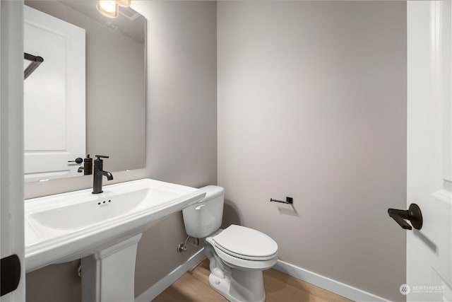 bathroom with toilet, wood finished floors, and baseboards