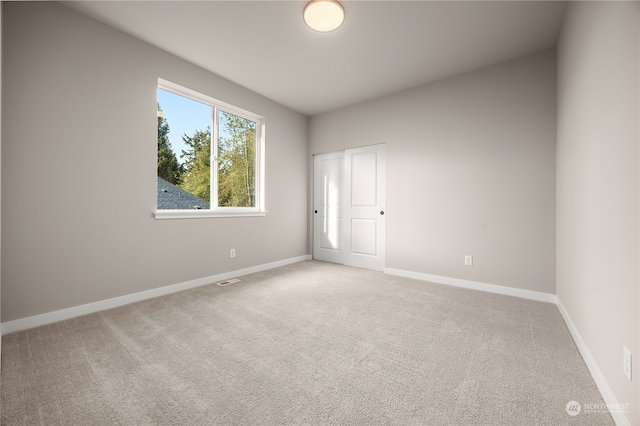 spare room featuring visible vents, light colored carpet, and baseboards