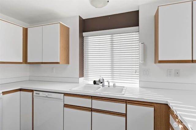 kitchen with white dishwasher, sink, and white cabinetry