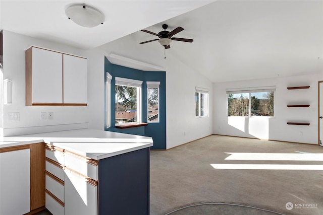 kitchen featuring white cabinetry, lofted ceiling, plenty of natural light, and light carpet