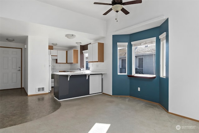 kitchen with sink, a breakfast bar area, kitchen peninsula, ceiling fan, and white cabinets