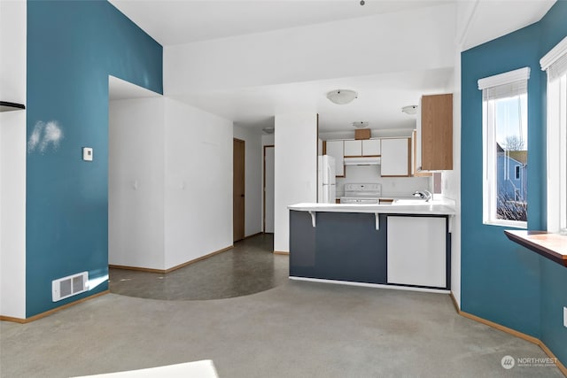 kitchen with sink, white cabinetry, a kitchen breakfast bar, kitchen peninsula, and white appliances