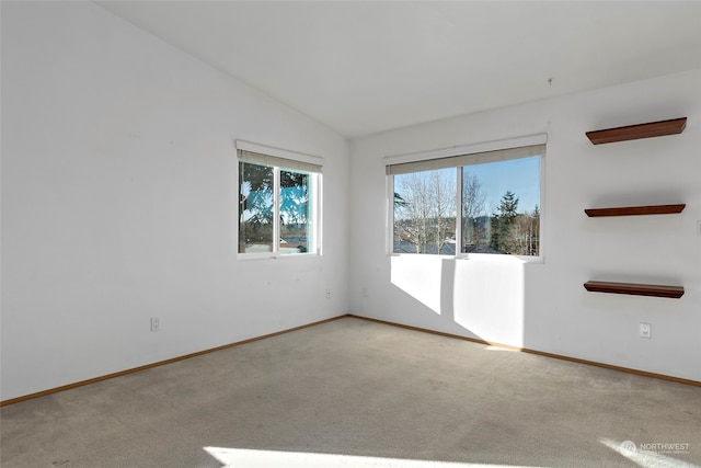 spare room with light colored carpet and vaulted ceiling