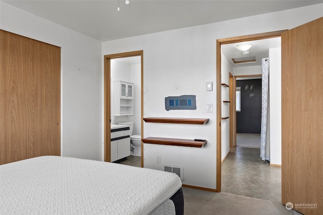 bedroom featuring concrete flooring and connected bathroom