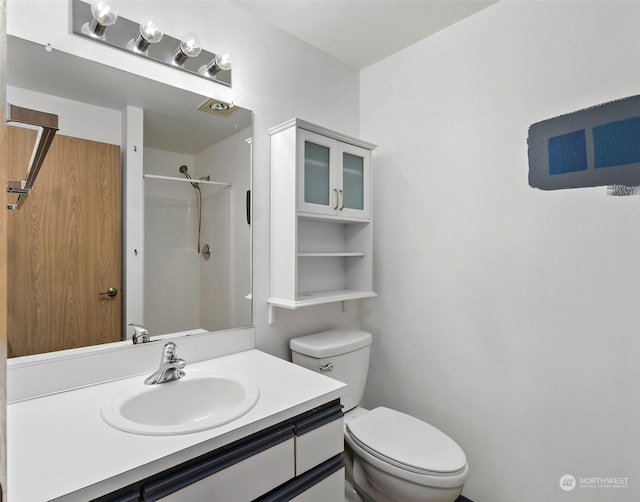 bathroom with walk in shower, vanity, and toilet