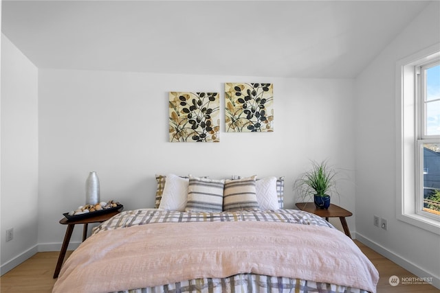 bedroom with wood-type flooring and vaulted ceiling