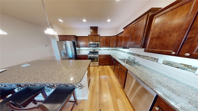 kitchen with pendant lighting, sink, a breakfast bar area, stainless steel appliances, and light stone countertops