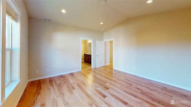 spare room featuring vaulted ceiling and light hardwood / wood-style floors