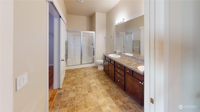 bathroom featuring vanity, a shower with shower door, and toilet