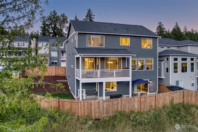 back house at dusk featuring a balcony