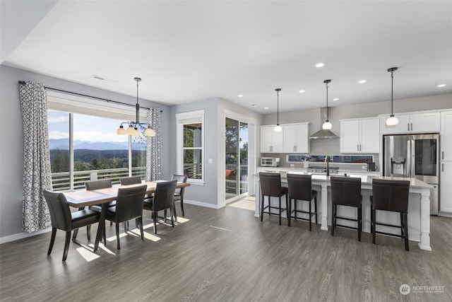 kitchen with white cabinetry, decorative light fixtures, a center island with sink, dark hardwood / wood-style flooring, and a mountain view