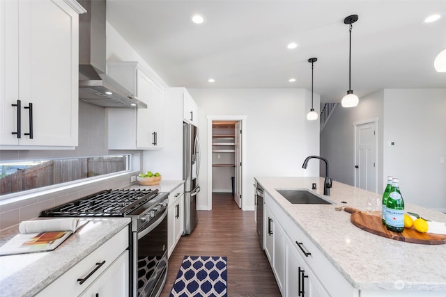 kitchen with sink, a kitchen island with sink, stainless steel appliances, light stone countertops, and wall chimney exhaust hood