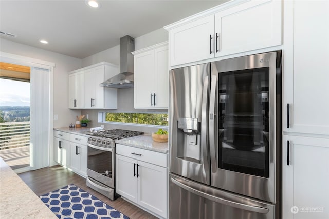 kitchen with wall chimney range hood, dark hardwood / wood-style floors, white cabinets, and appliances with stainless steel finishes