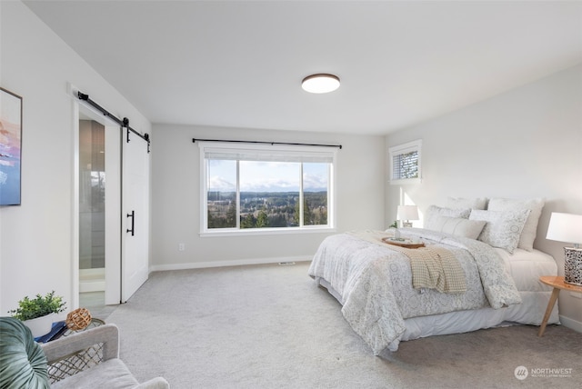 carpeted bedroom with a barn door and connected bathroom