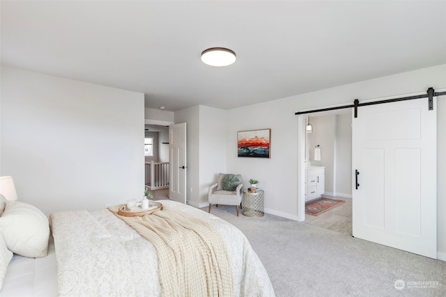 bedroom with ensuite bath, light colored carpet, and a barn door