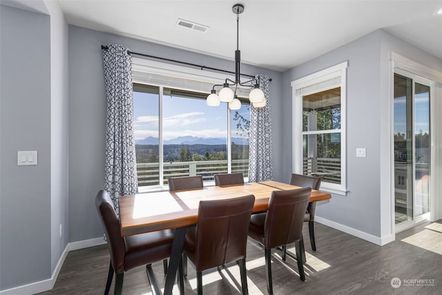 dining room with a mountain view, a notable chandelier, plenty of natural light, and dark hardwood / wood-style floors