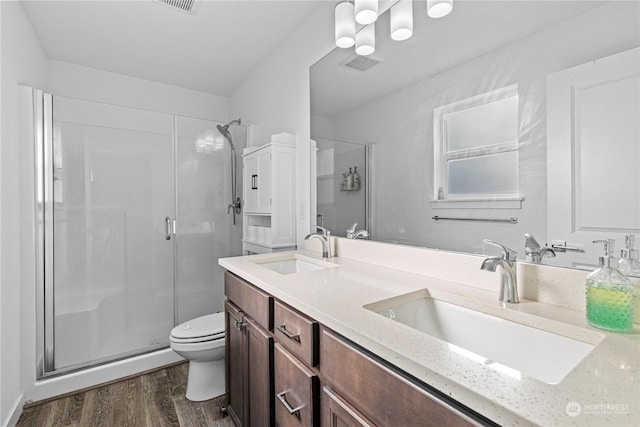 bathroom featuring vanity, toilet, a shower with shower door, and hardwood / wood-style floors