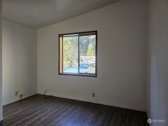 empty room with dark wood-type flooring and vaulted ceiling