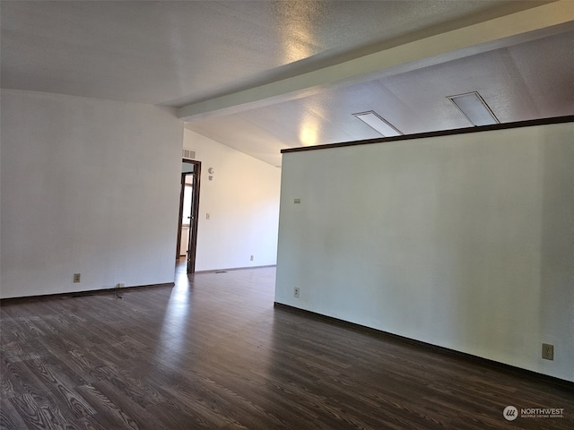 spare room featuring dark hardwood / wood-style flooring and vaulted ceiling with beams