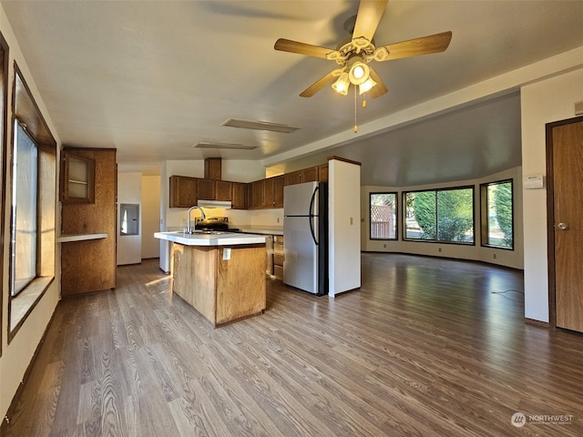 kitchen with stainless steel refrigerator, sink, a kitchen bar, hardwood / wood-style flooring, and a kitchen island with sink