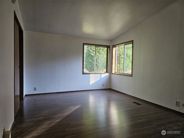 unfurnished room with dark hardwood / wood-style floors and vaulted ceiling